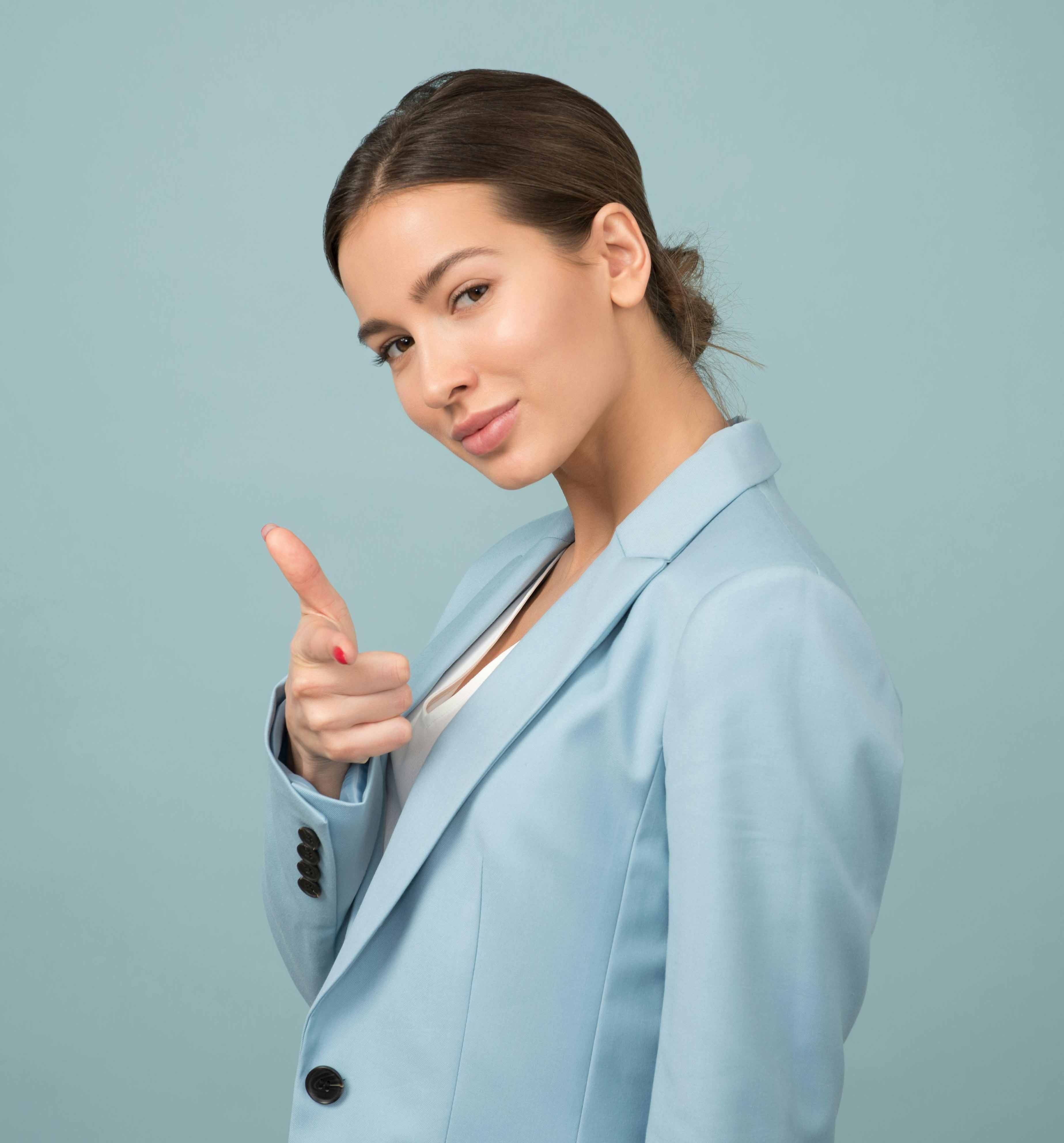 Woman in a blue blazer confidently pointing toward the viewer
