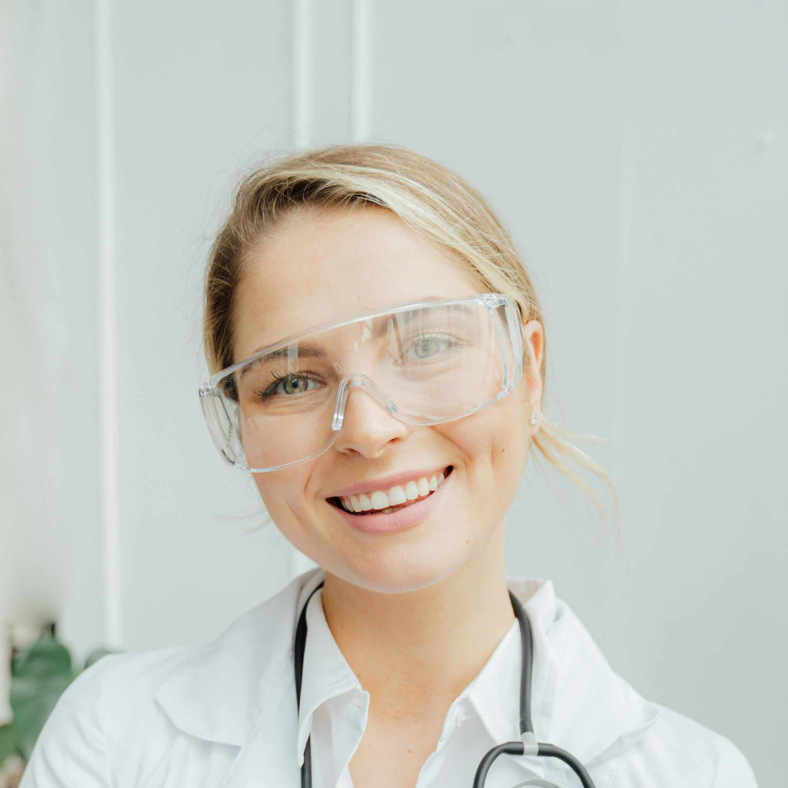 Doctor wearing protective glasses smiling at the viewer