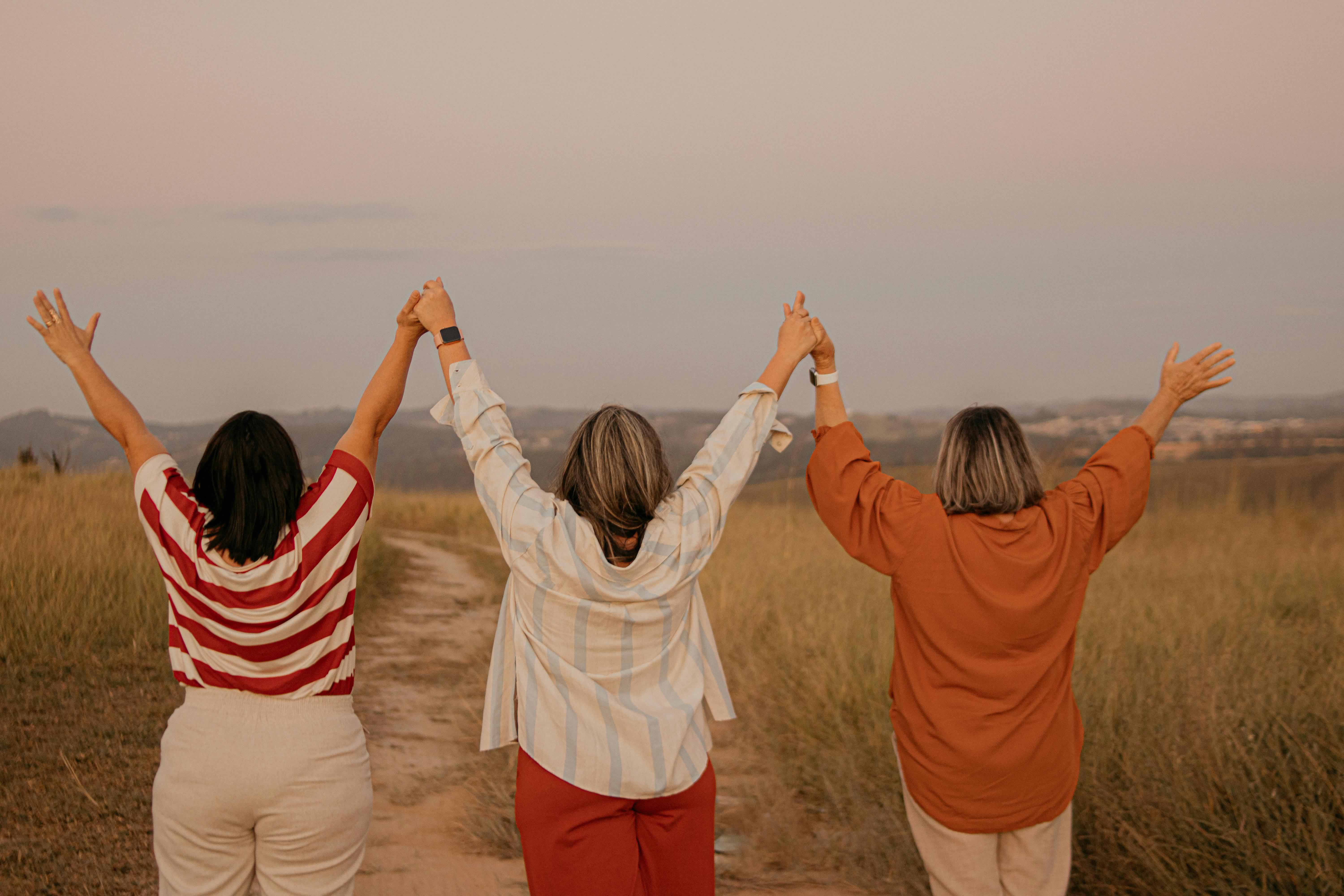 Group of three people holding there hands high in the air