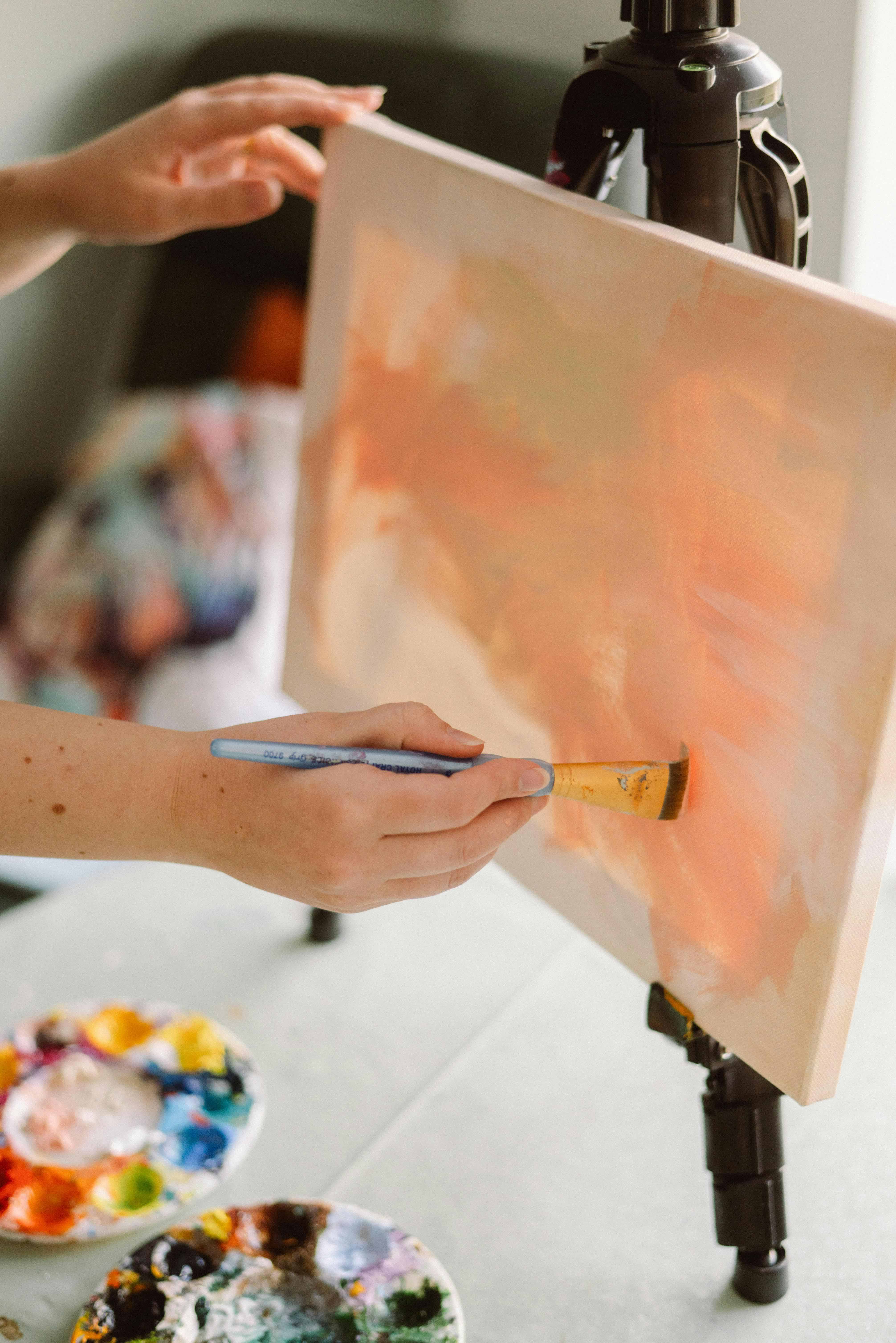 A canvas being painted with pink paint in an art studio