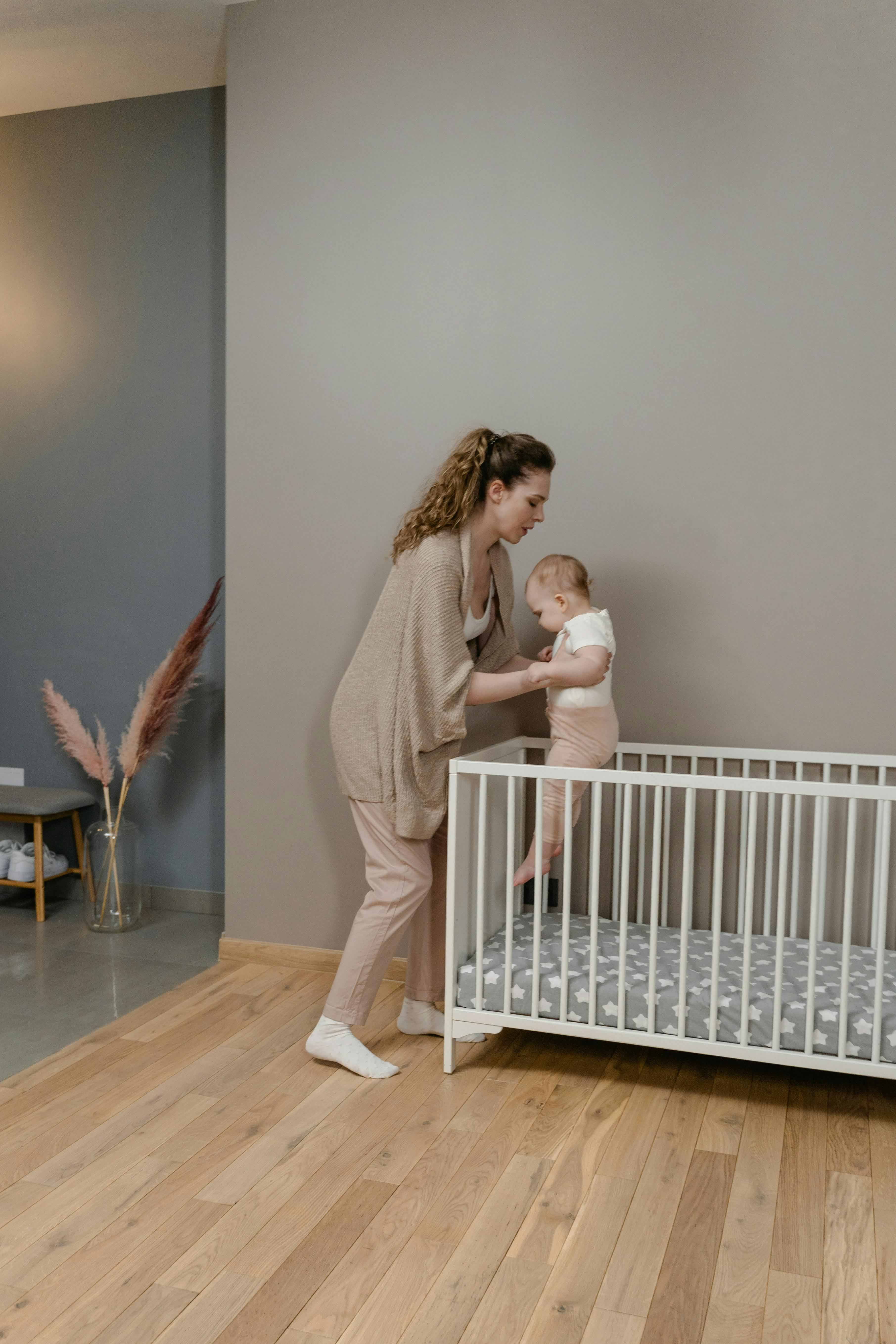 A person putting a baby in the crib late at night