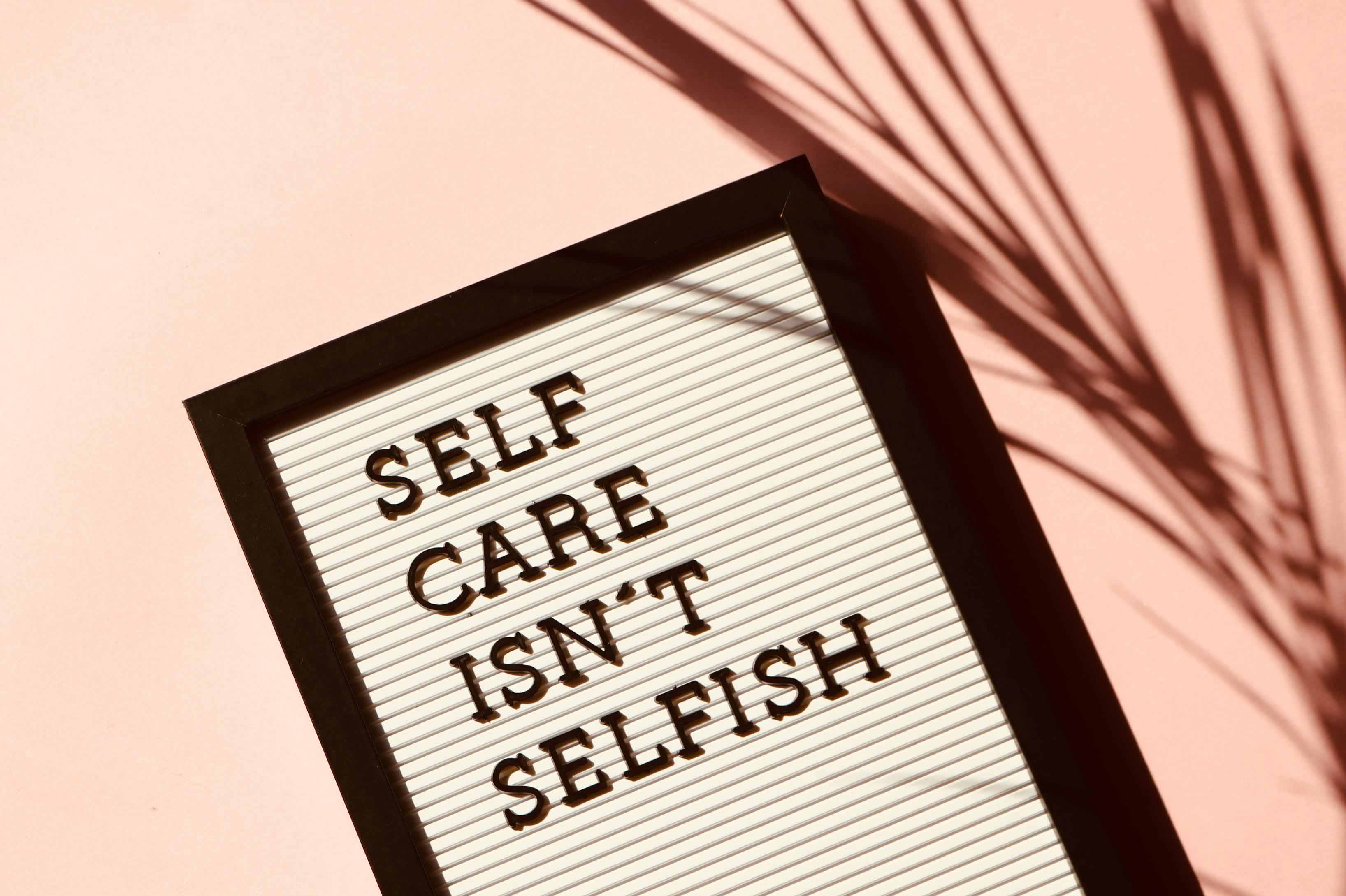 Sign that says Self Care Isn't Selfish with a pink background