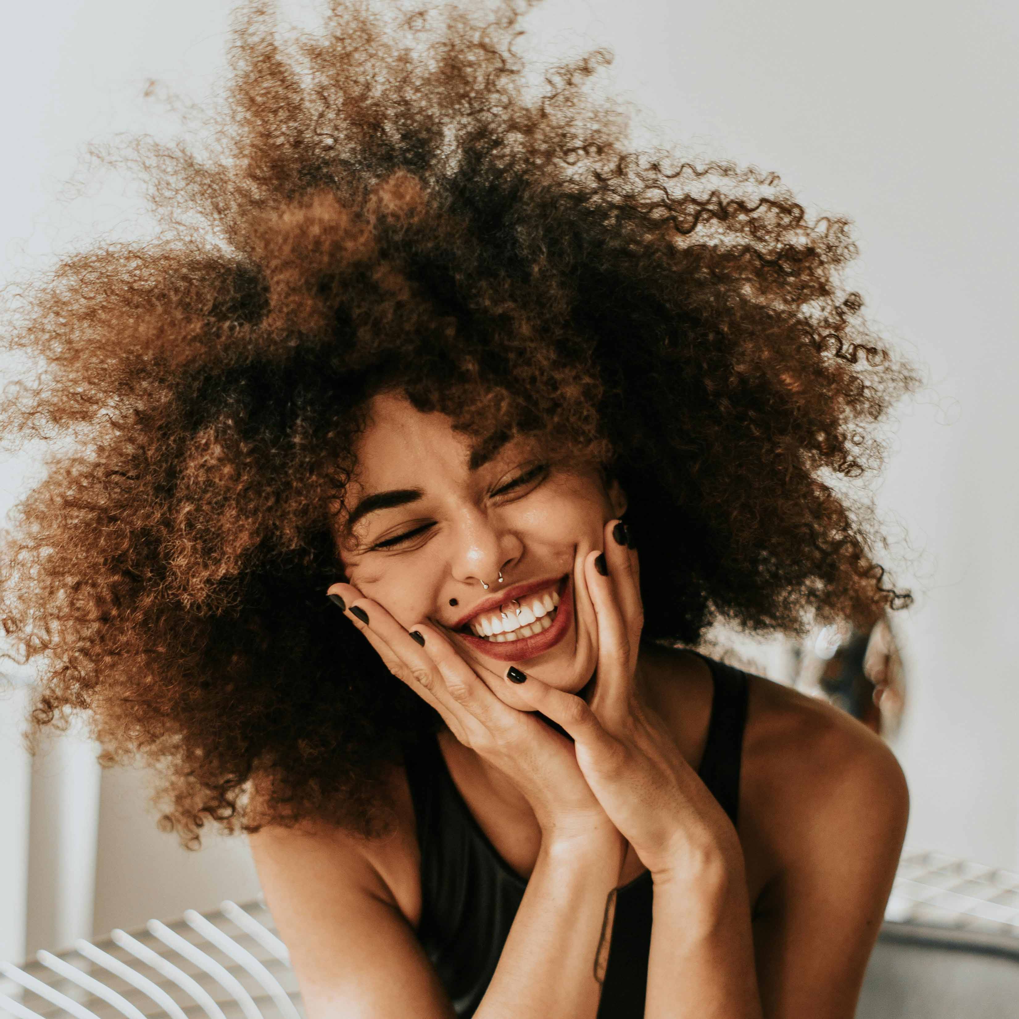 Smiling woman gently holding her face, radiating happiness and confidence