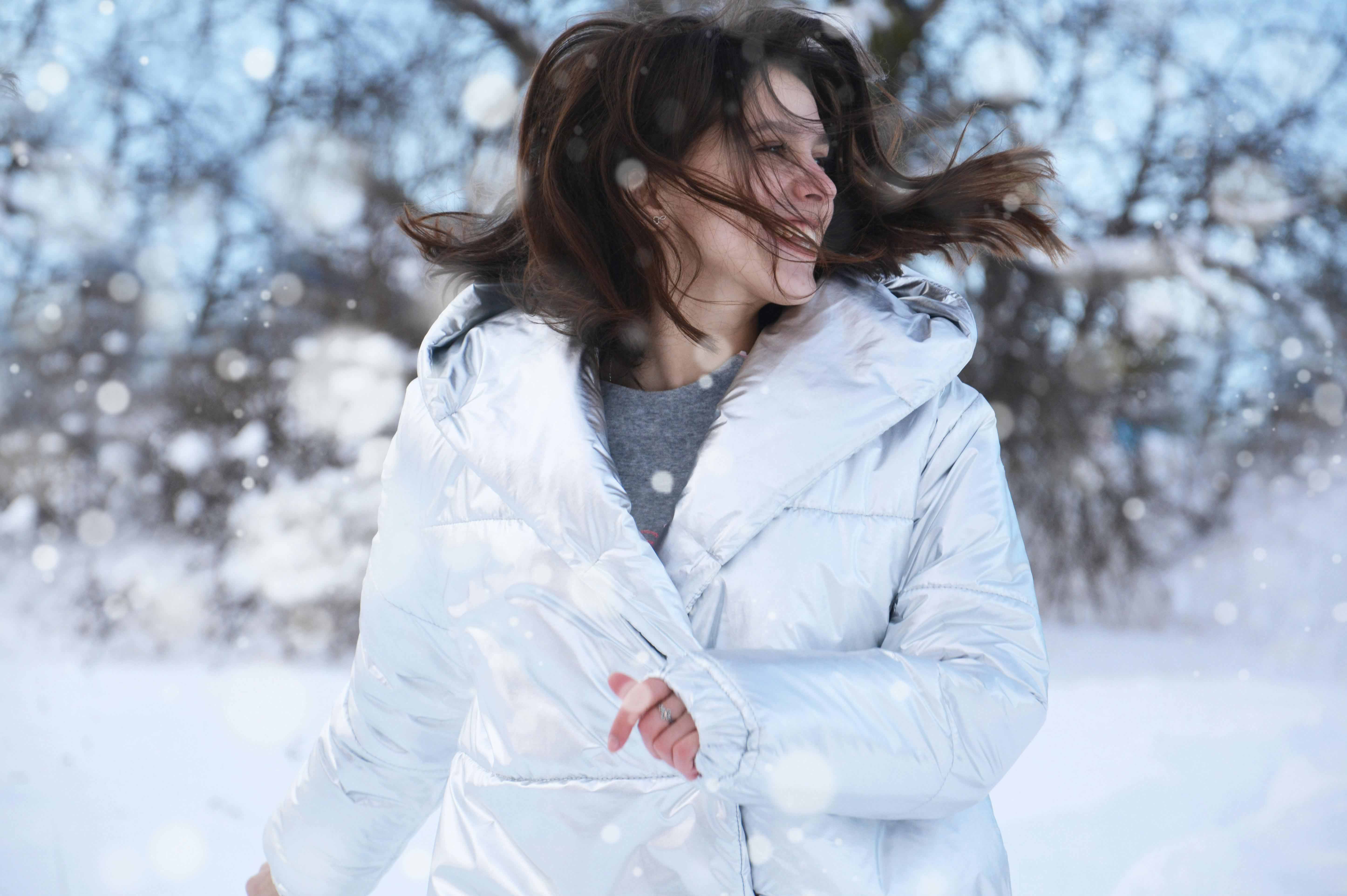 Women running in a white coat in the snow smiling